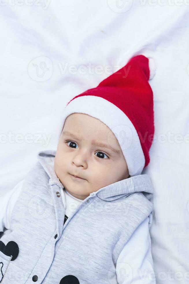 peu Père Noël. 1 année vieux bébé garçon dans Père Noël claus casquette. Noël des gamins photo