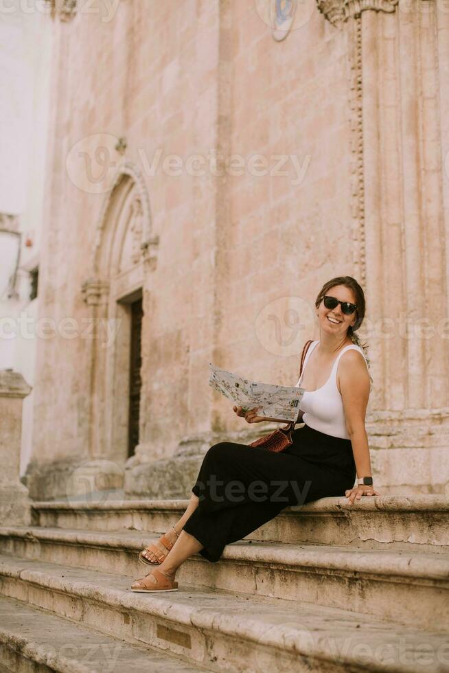 femelle touristique avec ville carte par le église san Francesco dassisi dans ostuni, Italie photo