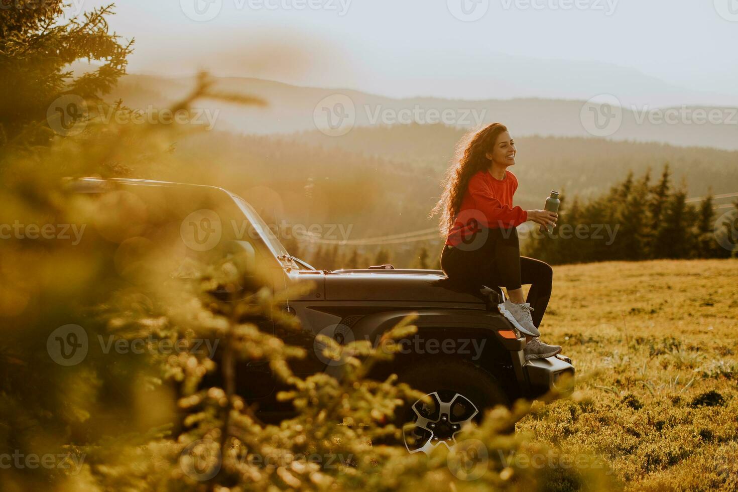 jeune femme se reposant sur un capot de véhicule tout-terrain à la campagne photo