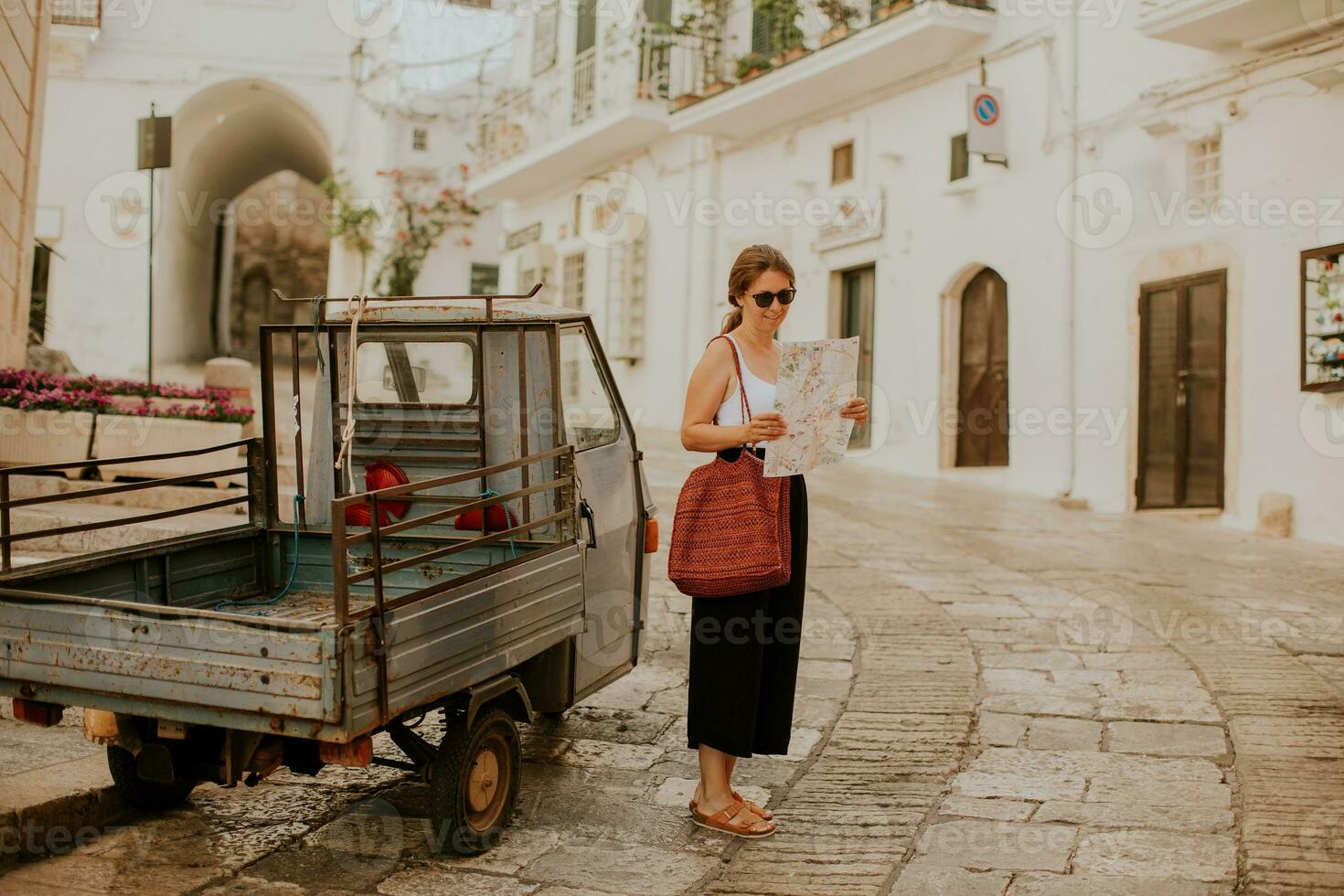 femelle touristique avec papier ville carte sur étroit des rues de ostuni, Italie photo