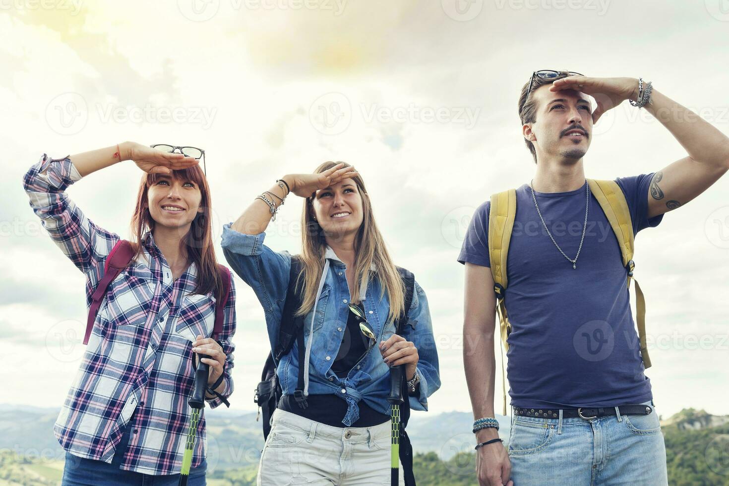 groupe de Jeune adultes regards à le horizon pendant randonnée photo