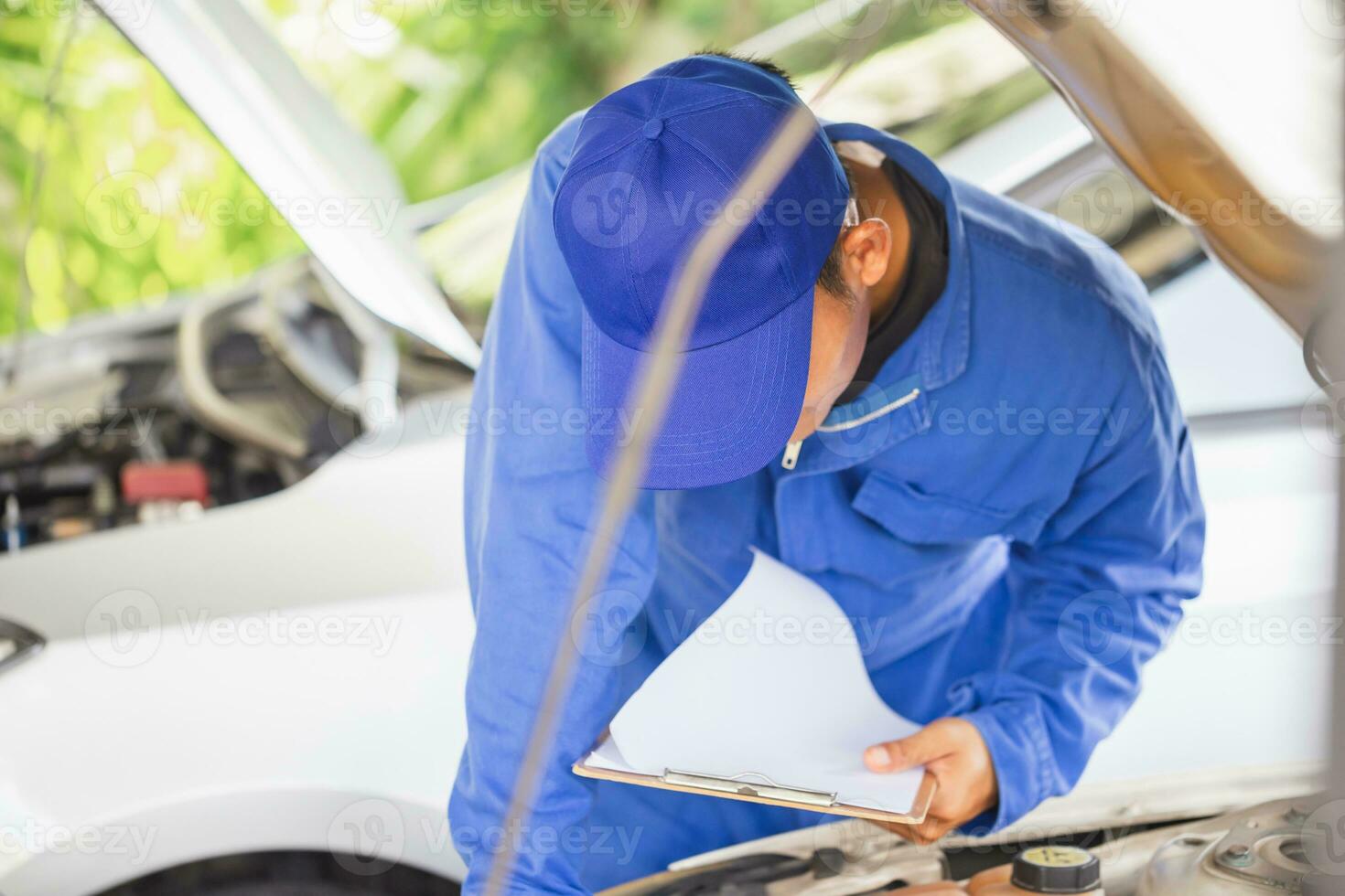 le réparateur de voitures vérifie le niveau d'huile moteur dans l'atelier  automobile, l'inspection des travailleurs de la voiture d'entretien  contrôle les moteurs de véhicules à huile par test de jauge à la