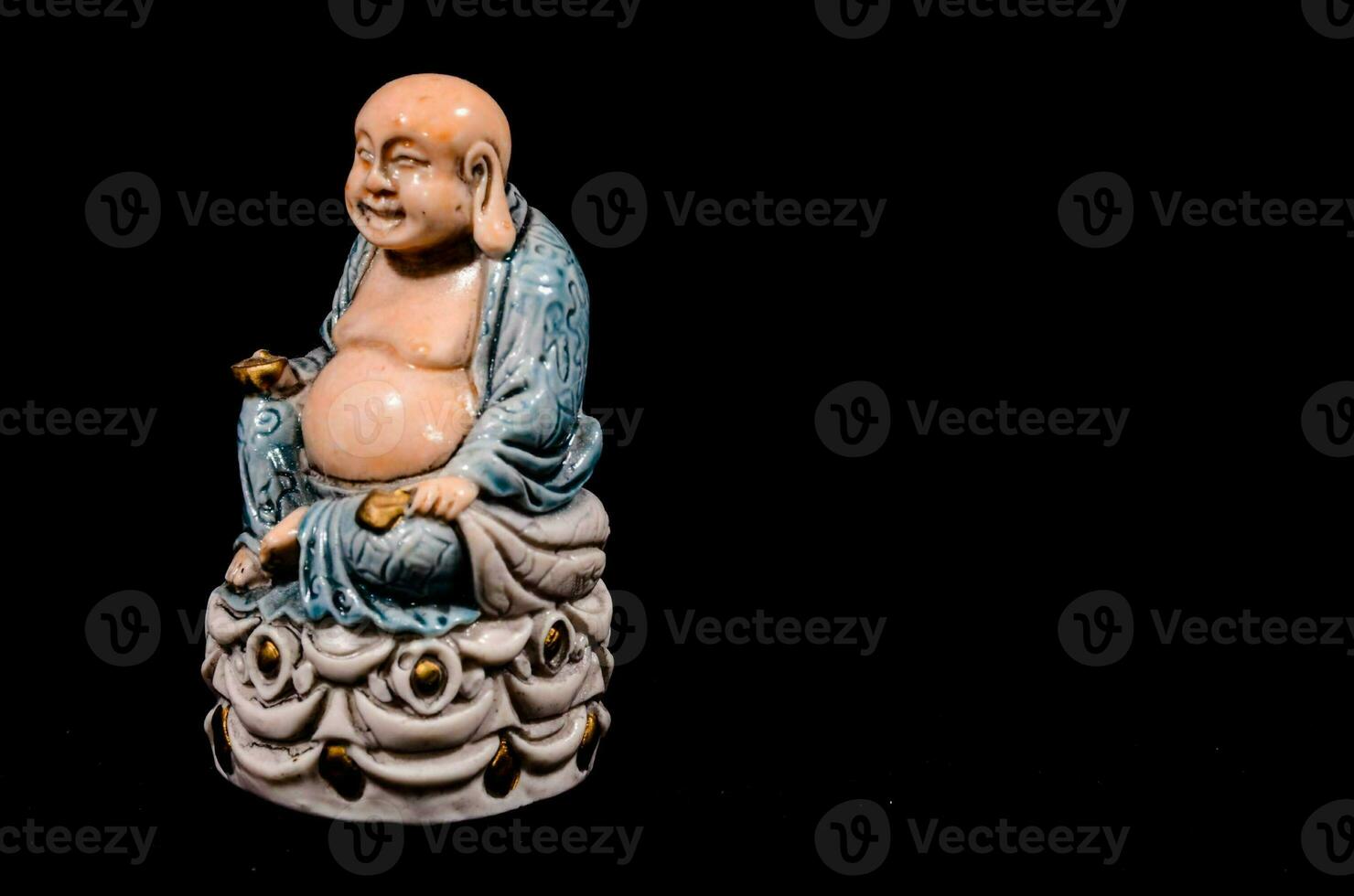 une statue de une en riant Bouddha séance sur une noir Contexte photo