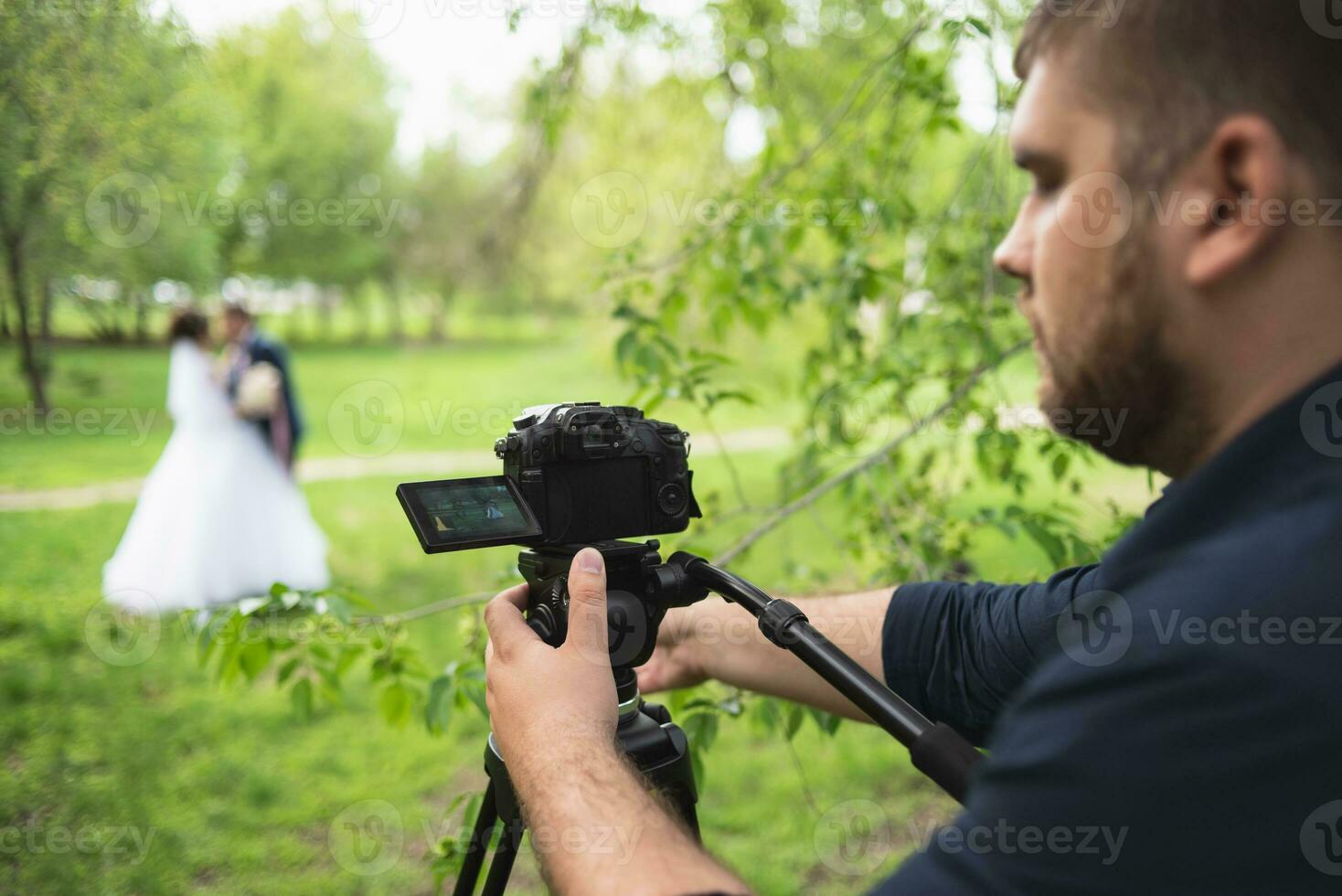 le vidéaste pousses le les mariés dans le jardin dans le été. photo