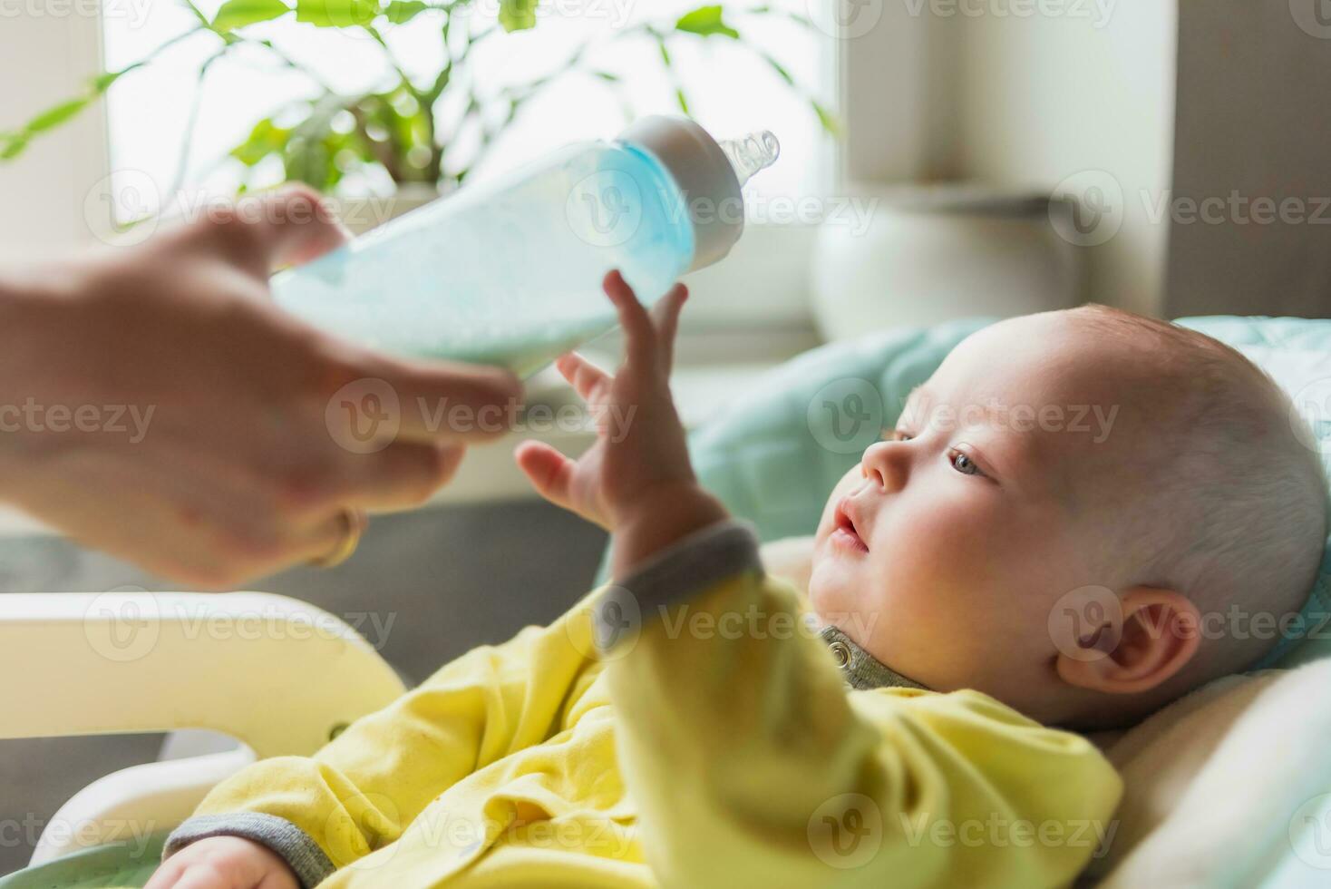 mère alimente le bébé. le bambin les boissons Lait de une bouteille . photo
