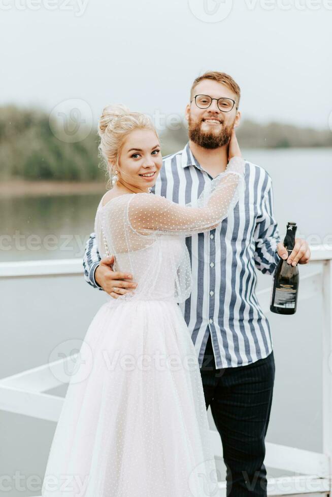 Jeune jeunes mariés étreindre sur le jetée par le l'eau. photo