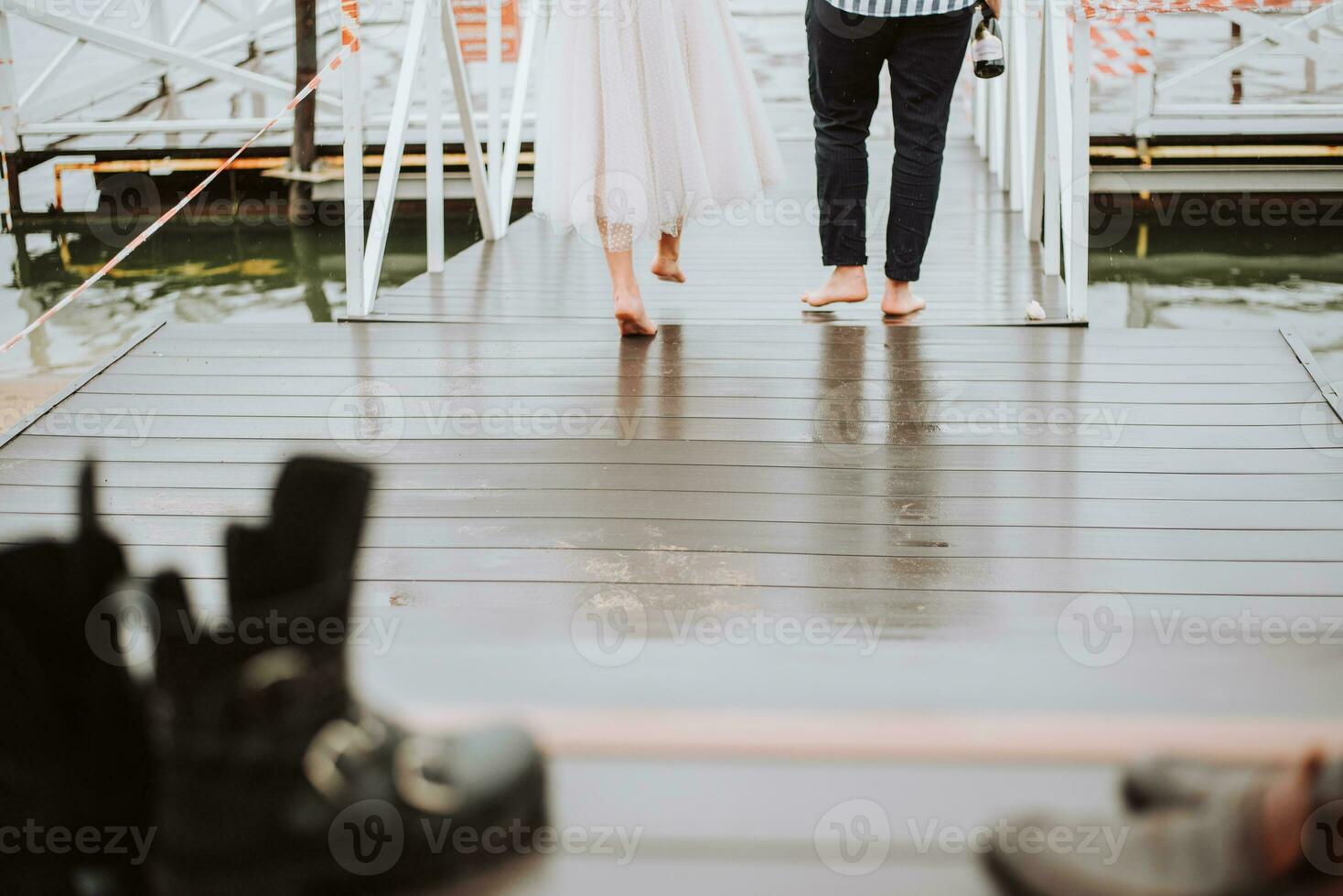 pieds de le jeunes mariés sur le Contexte de le jetée.la la mariée et jeune marié aller pieds nus le long de le quai. photo