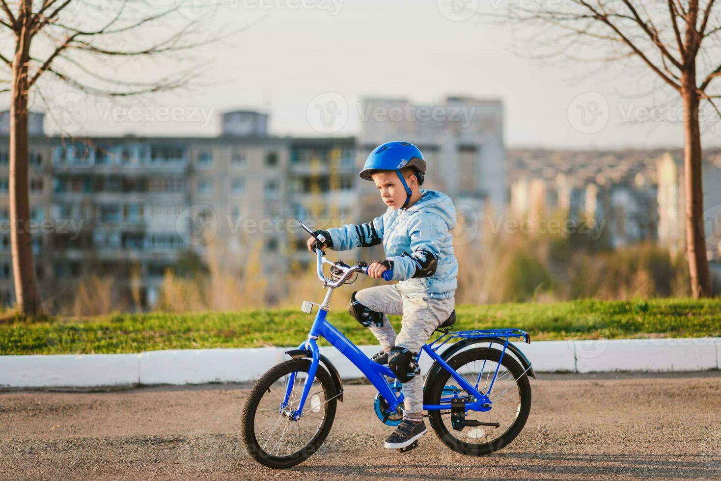 peu garçon dans casque monte une vélo sur une ensoleillé journée photo