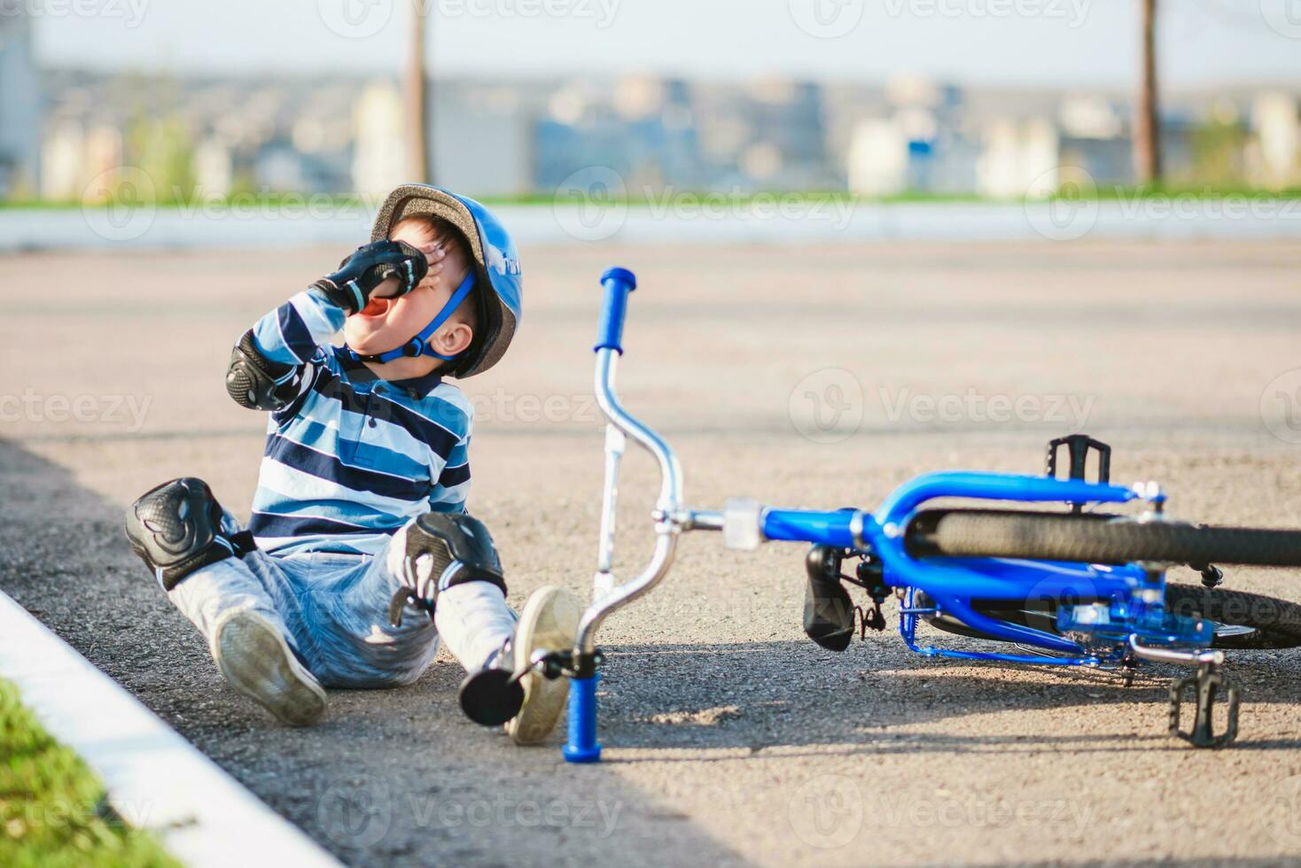 une petit enfant est tombée de une vélo sur le route, pleurs et en hurlant dans douleur. photo