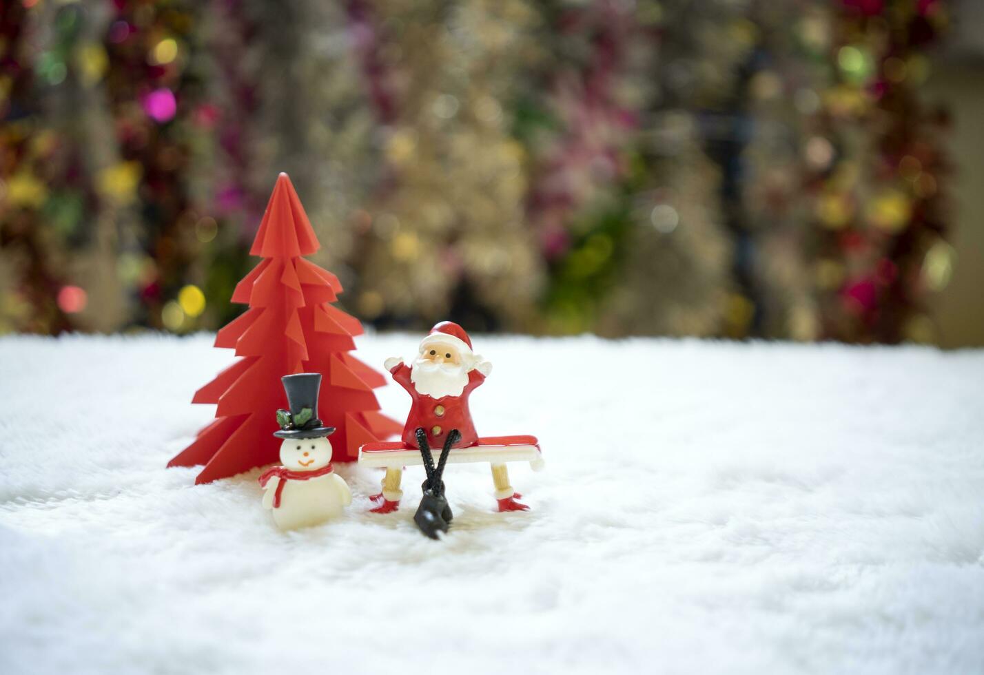 sata séance sur rouge banc avec bonhomme de neige dans de face de rouge origami Noël arbre attendre pour marrant festival, Noël et Nouveau année concept. photo