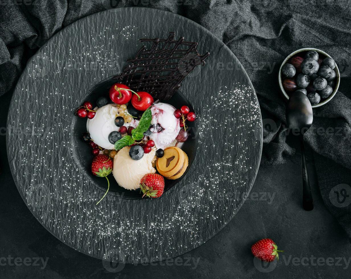 vanille la glace crème boules avec Frais baies sur noir assiette photo