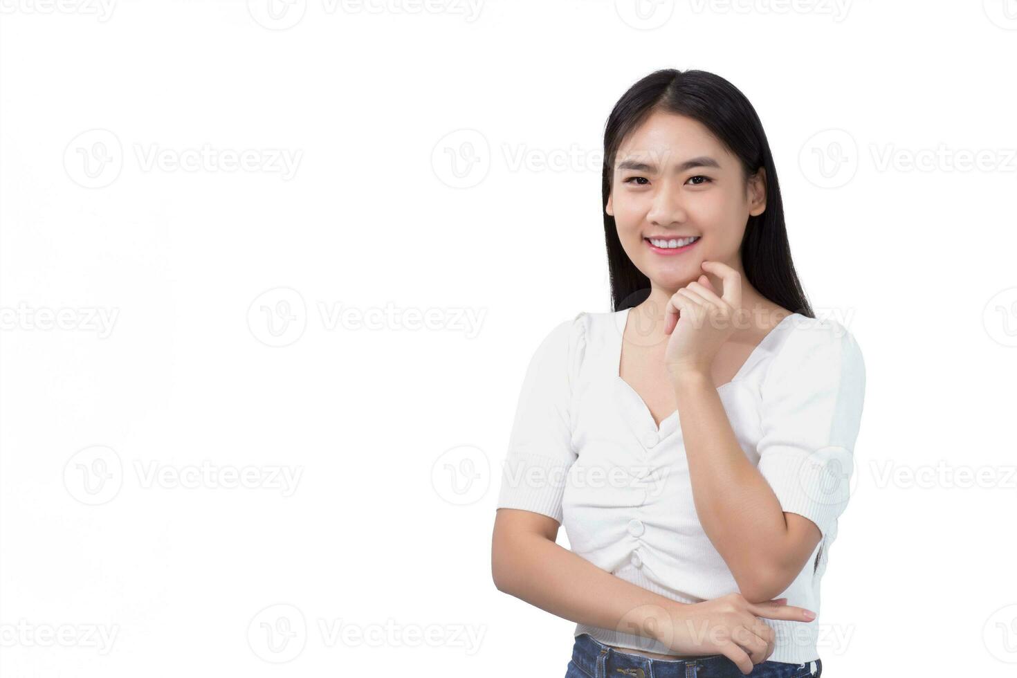 portrait sur de soi Jeune asiatique femme dans blanc chemise touche sa visage et sourit isolé sur blanc Contexte. photo