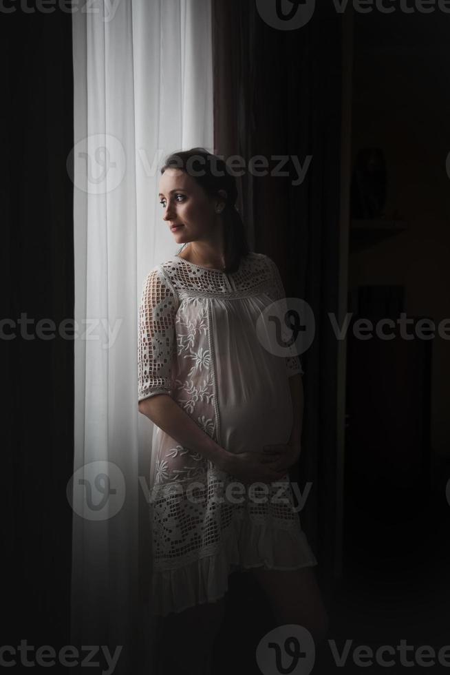 femme enceinte heureuse près d'une fenêtre photo