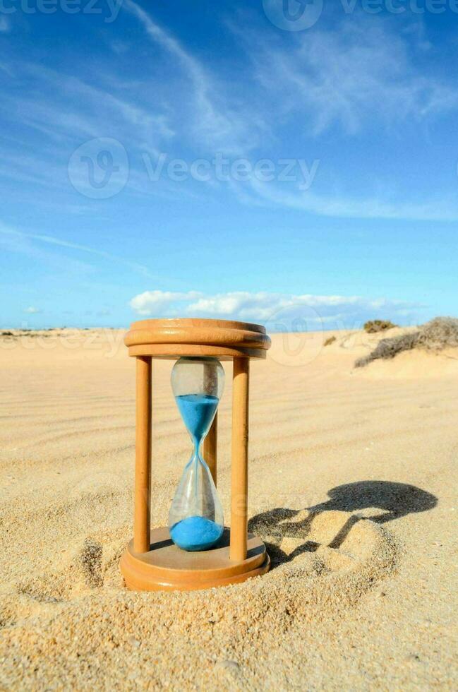 un Sablier dans le le sable sur une ensoleillé journée photo