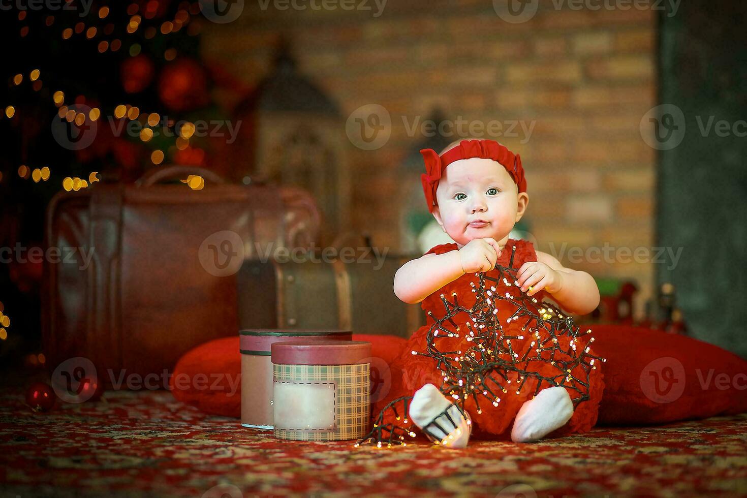 peu fille dans rouge robe contre Contexte de Noël arbre détient Noël guirlande dans sa mains. bébé 6 mois vieux fête Noël. photo