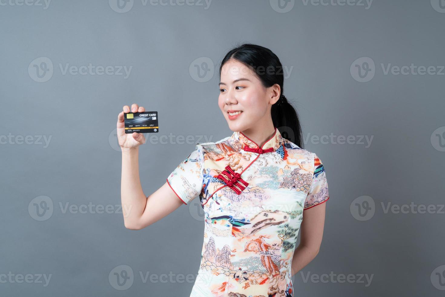 une femme asiatique porte une robe traditionnelle chinoise avec une main tenant une carte de crédit photo