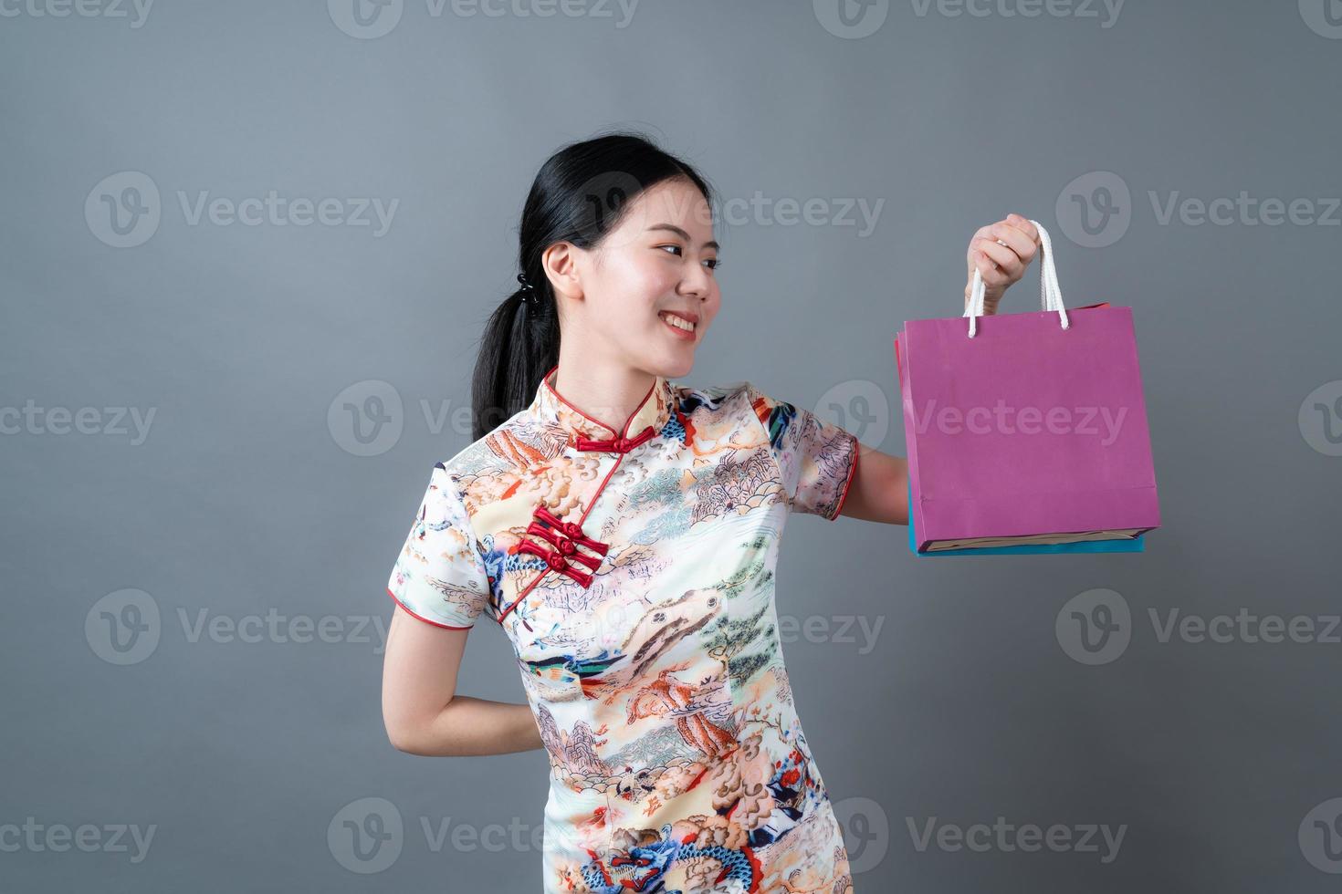 une femme asiatique porte une robe traditionnelle chinoise avec une main tenant un sac à provisions photo