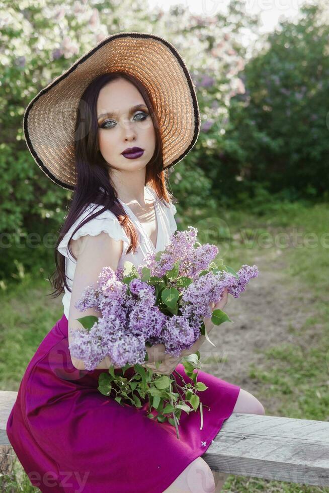 une à la mode fille avec foncé cheveux, une printemps portrait dans lilas tons dans été. brillant professionnel se maquiller. photo