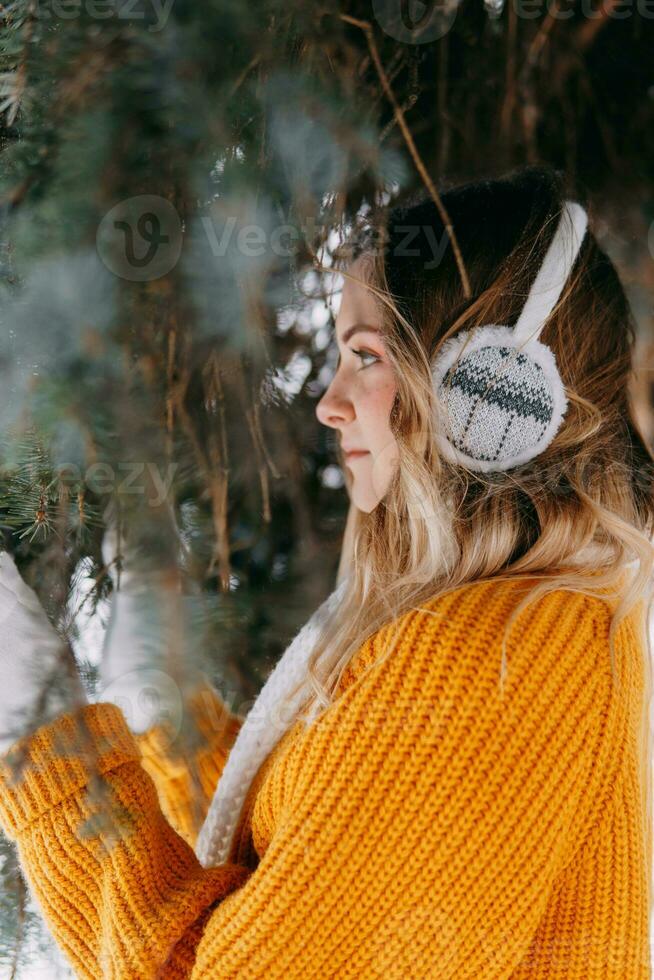 adolescent blond dans une Jaune chandail à l'extérieur dans l'hiver. une adolescent fille sur une marcher dans hiver vêtements dans une neigeux forêt photo