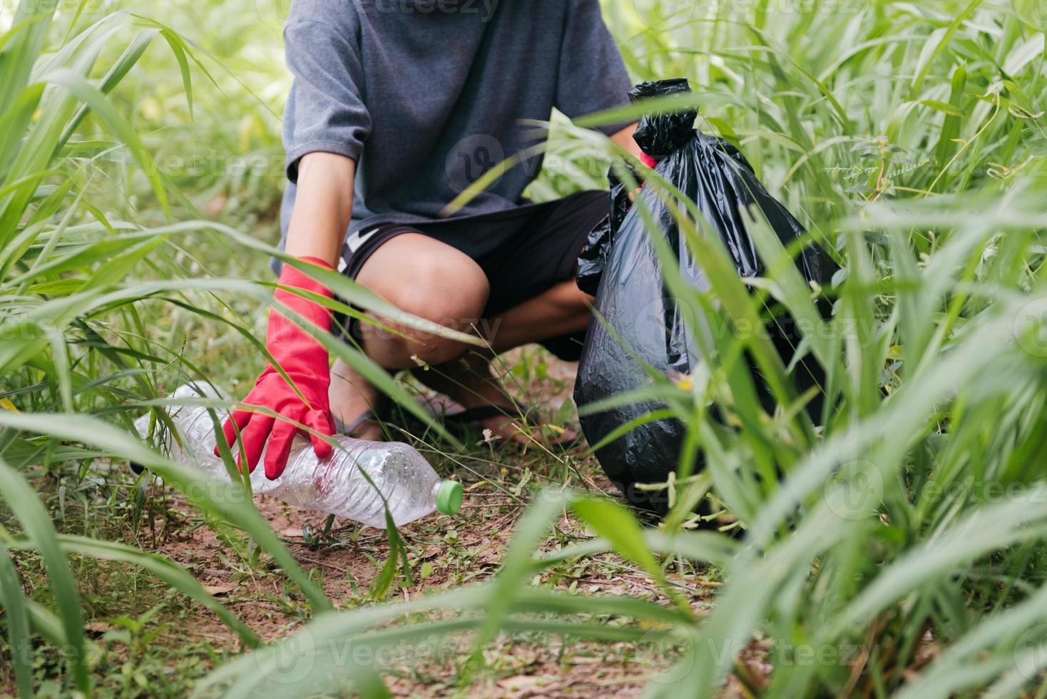 garçon homme main ramasser une bouteille en plastique dans la forêt. notion d'environnement. photo