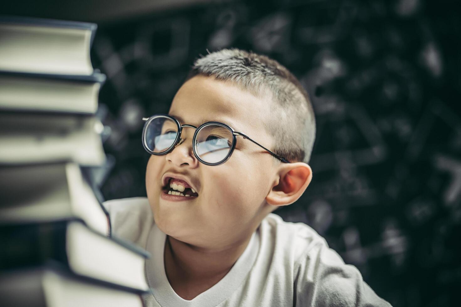 un garçon avec des lunettes assis dans la classe en comptant les livres photo