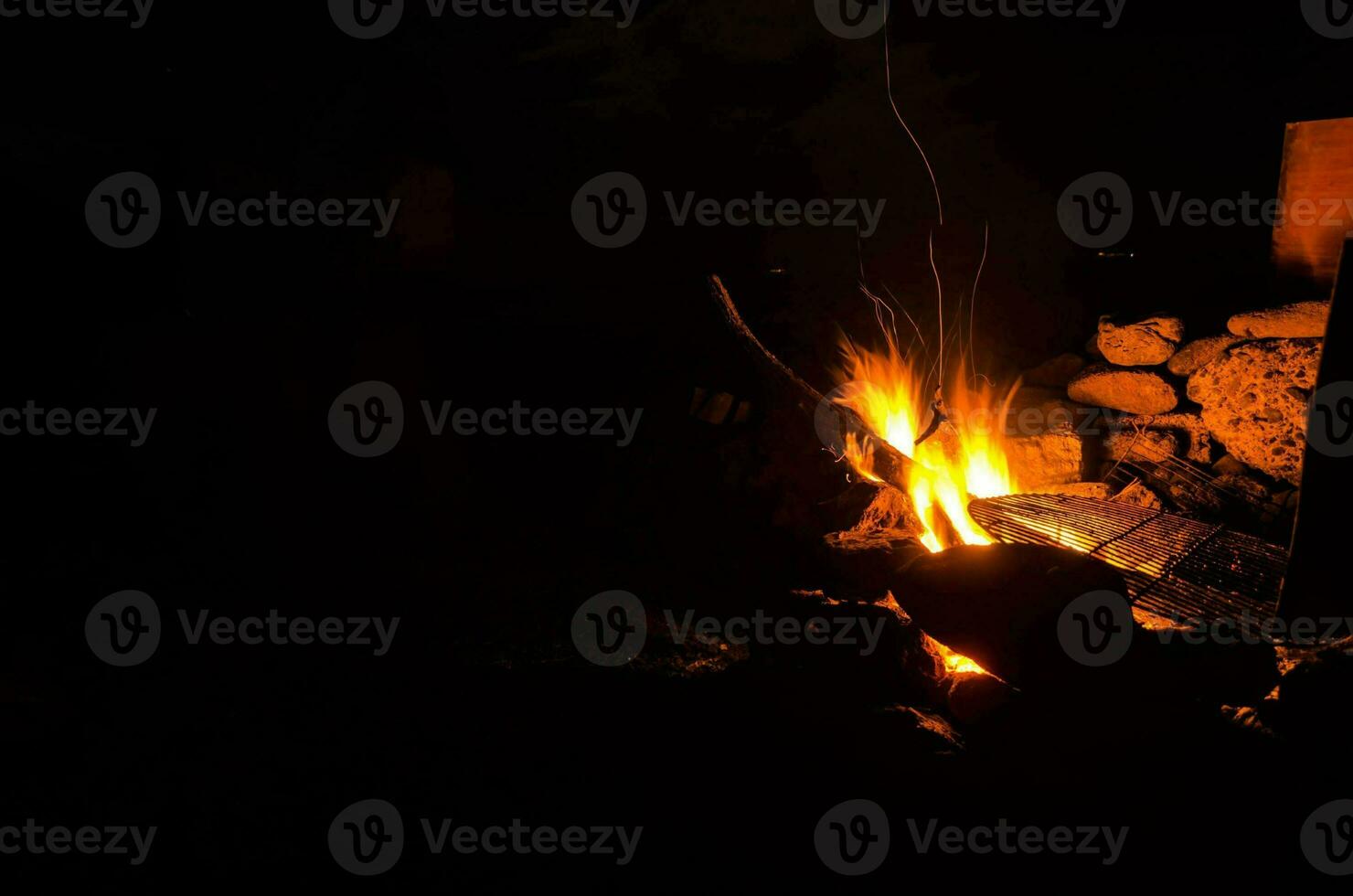 une feu de camp est allumé en haut à nuit avec une foncé ciel photo