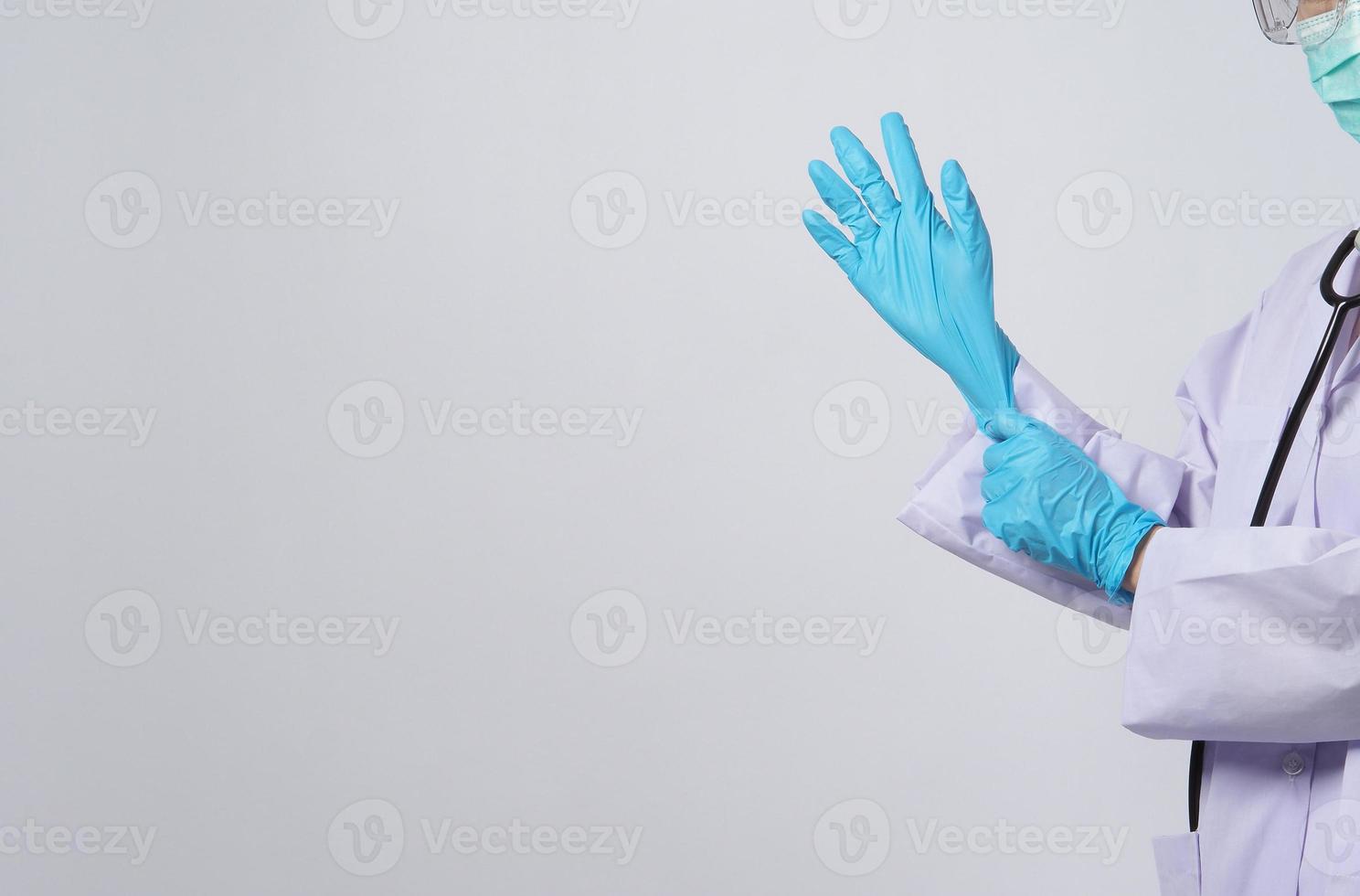 porter des gants. un médecin asiatique porte un gant pour les mains en caoutchouc nitrile bleu. photo