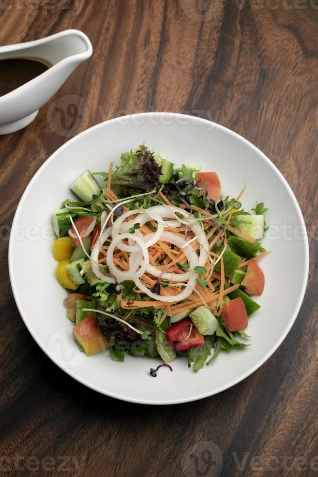 salade de jardin végétalienne de légumes mélangés biologiques frais avec sauce vinaigrette photo