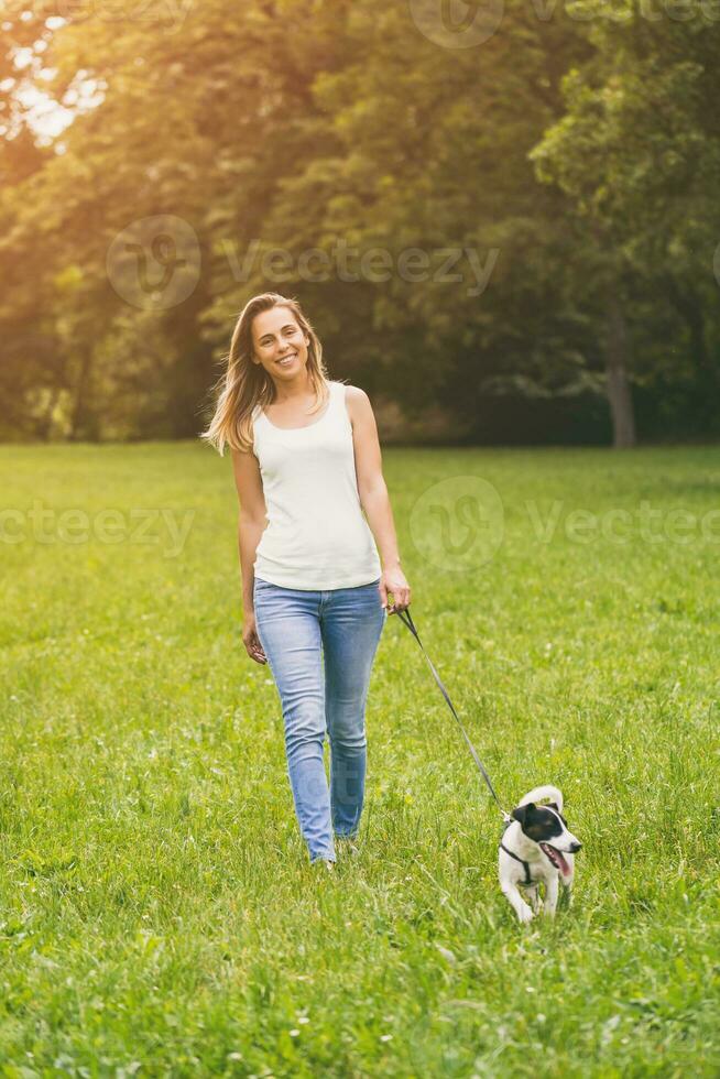 magnifique femme jouit en marchant avec sa mignonne chien jack Russell terrier dans le la nature photo