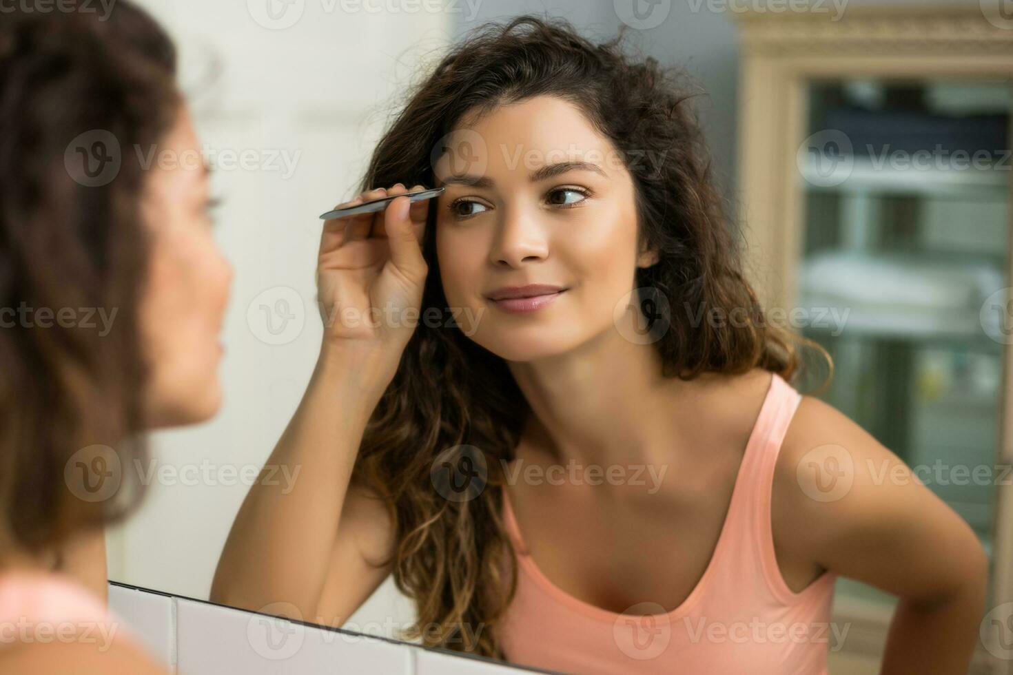 magnifique femme cueillette les sourcils dans salle de bains photo