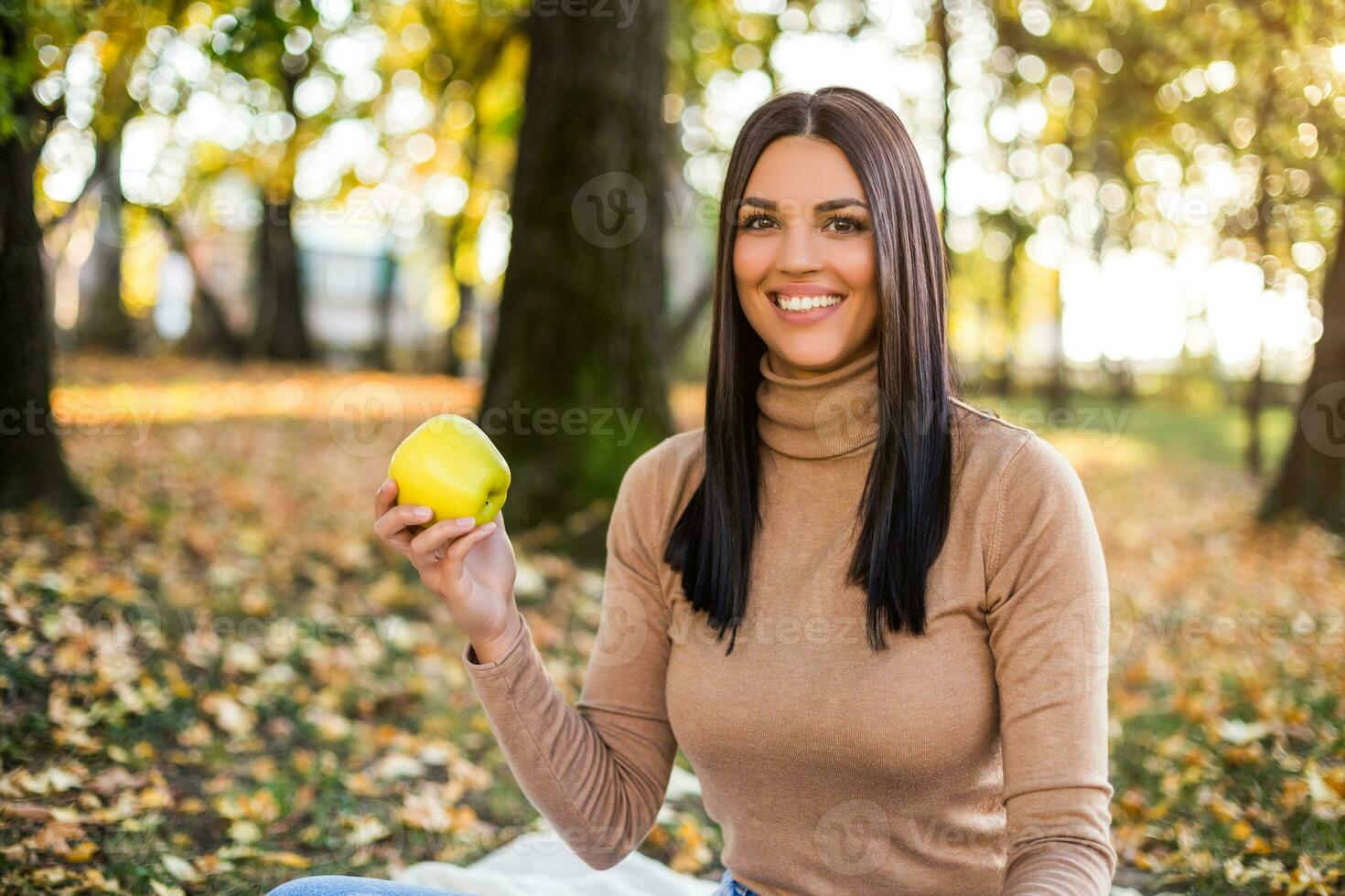 magnifique femme en mangeant Pomme tandis que jouit dans l'automne et repos dans le par photo