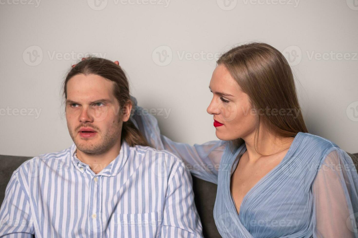 une magnifique femme dans lumière bleu vêtements avec rouge lèvres regards à une sérieux homme photo