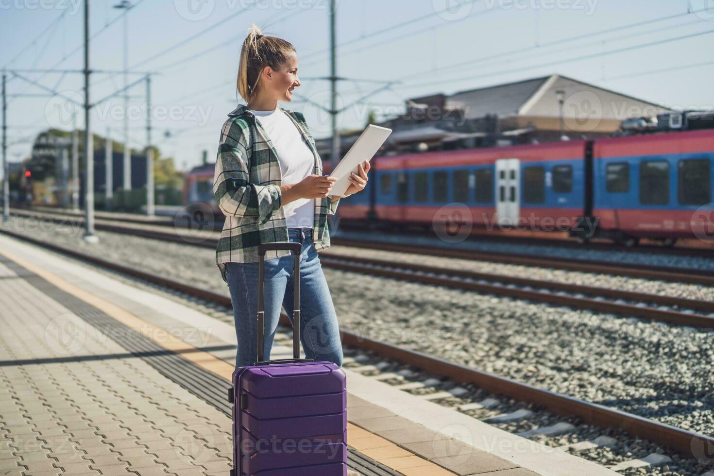 content femme en utilisant numérique tablette sur une train station photo