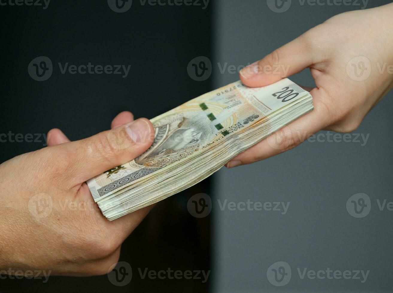 Masculin et femelle mains en portant une paquet de 200 zloty billets de banque. sélectif concentrer photo