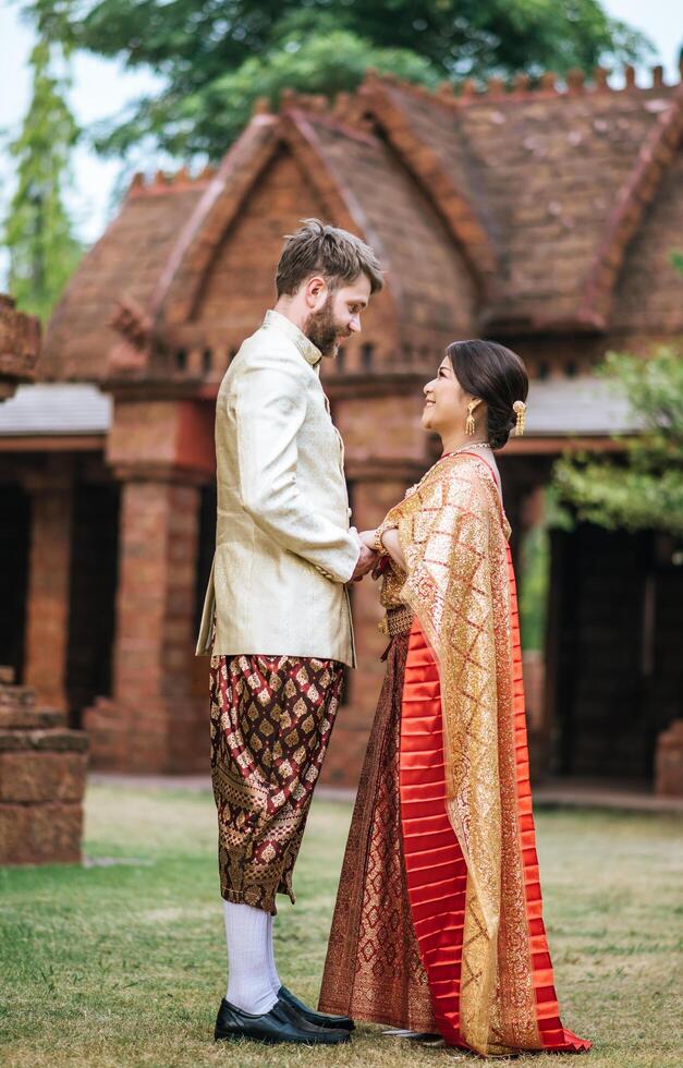 la mariée asiatique et le marié caucasien passent un moment romantique avec une robe thaïlandaise photo