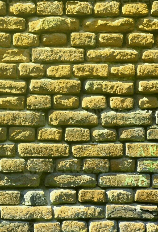 texture de mur vertical de plusieurs rangées de maçonnerie très ancienne en brique rouge. mur de briques brisé et endommagé avec des coins pincés photo