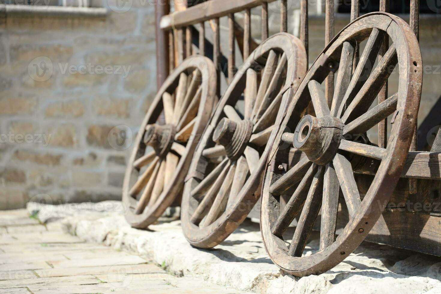 Trois vieux en bois roues pour cheval chariots penché contre une en bois mur photo