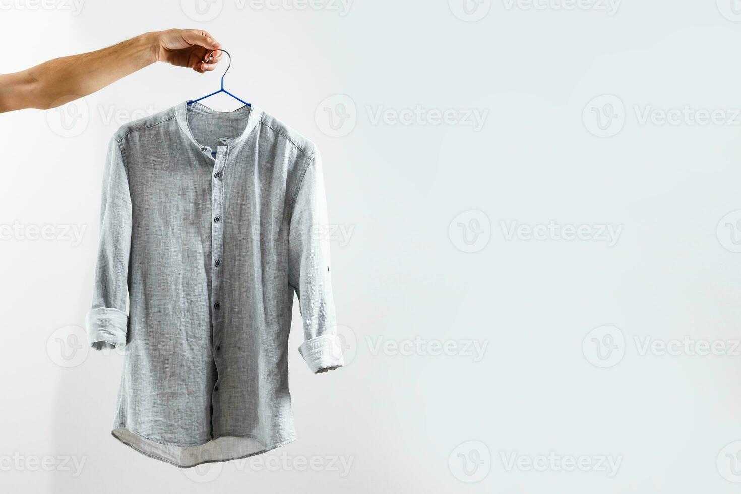 Pour des hommes équipage cou chemise. homme en portant une blanc chemise sur une vêtements cintre. sur une blanc Contexte photo