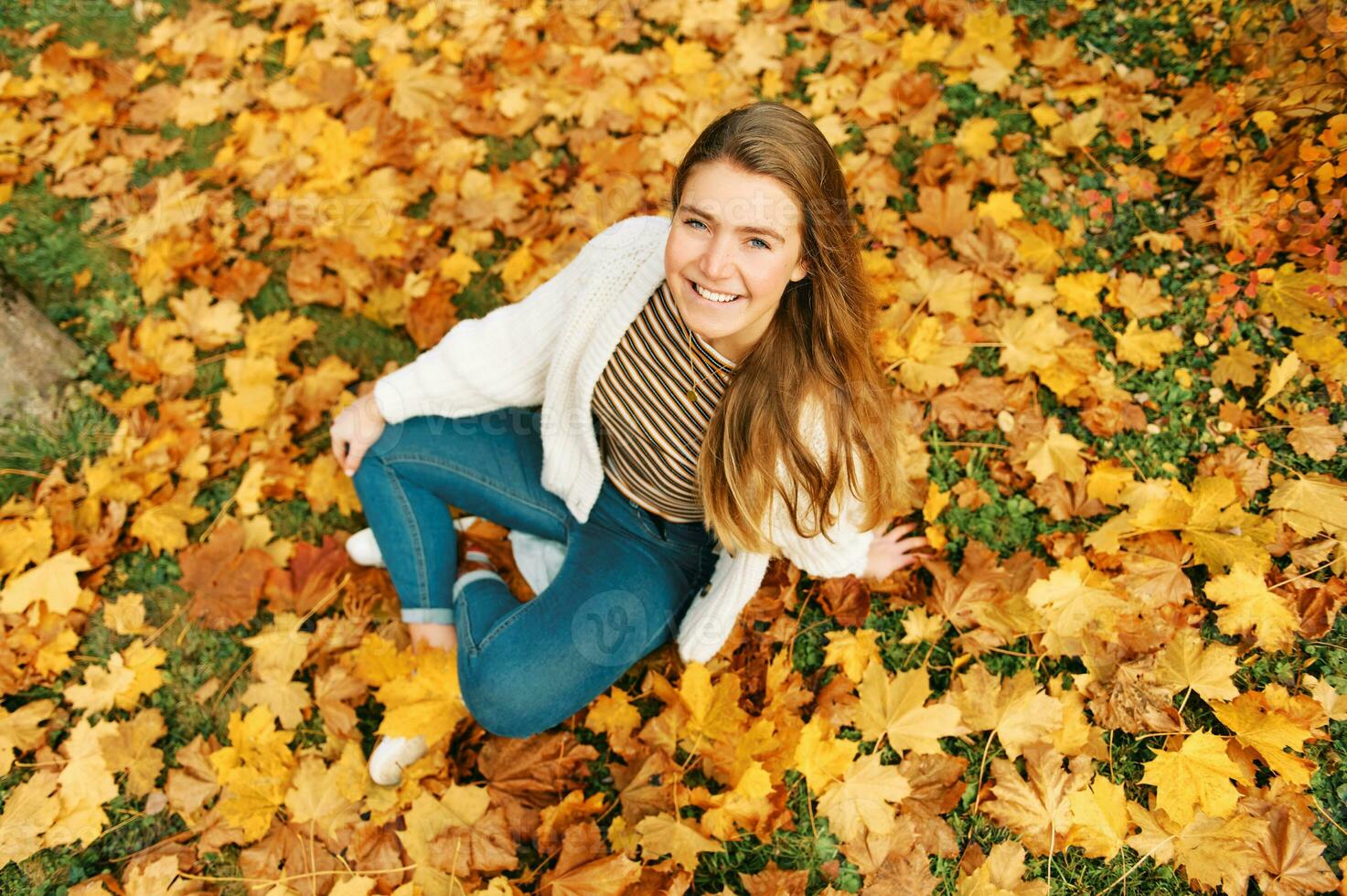 Haut vue l'automne portrait de content Jeune femelle modèle fille séance sur Jaune feuilles, à la recherche tout droit à caméra photo