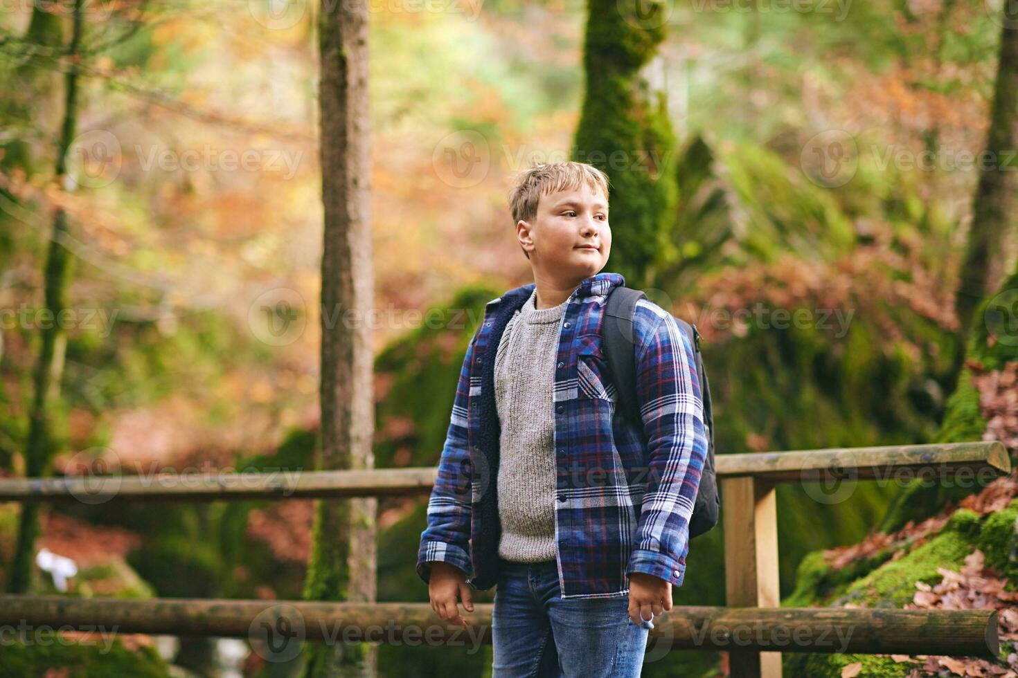 Extérieur portrait de content enfant garçon randonnée dans l'automne forêt, portant sac à dos photo