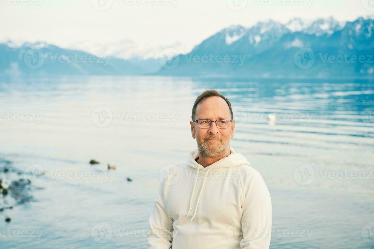 portrait de Beau homme admiratif magnifique Lac avec montagnes, portant blanc sweat-shirt photo