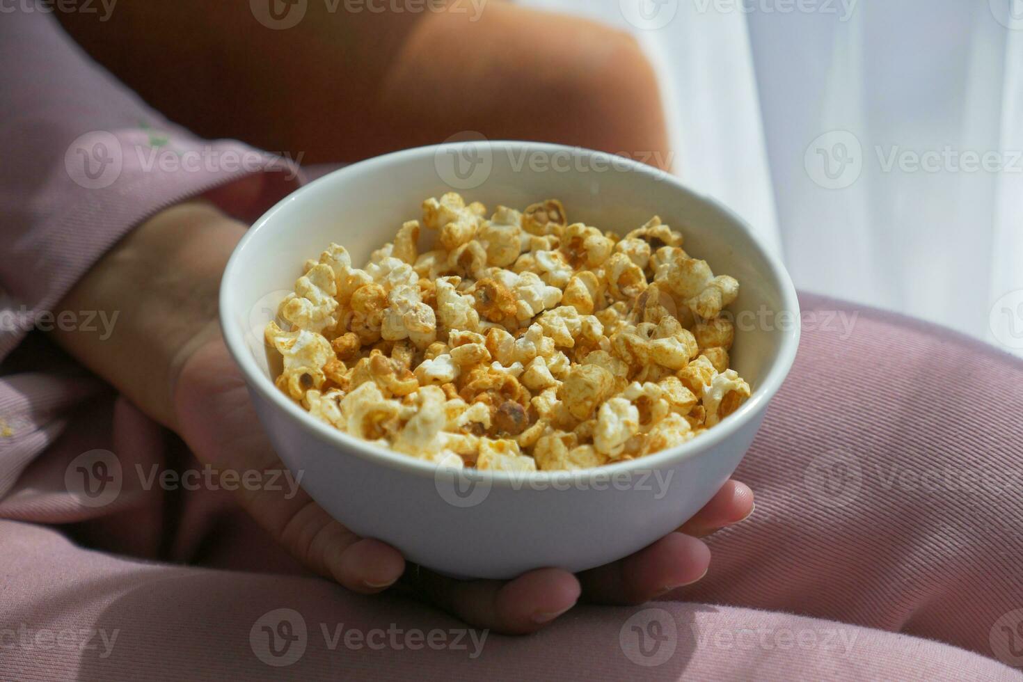 Jeune femmes en mangeant pop corn séance sur canapé à Accueil photo