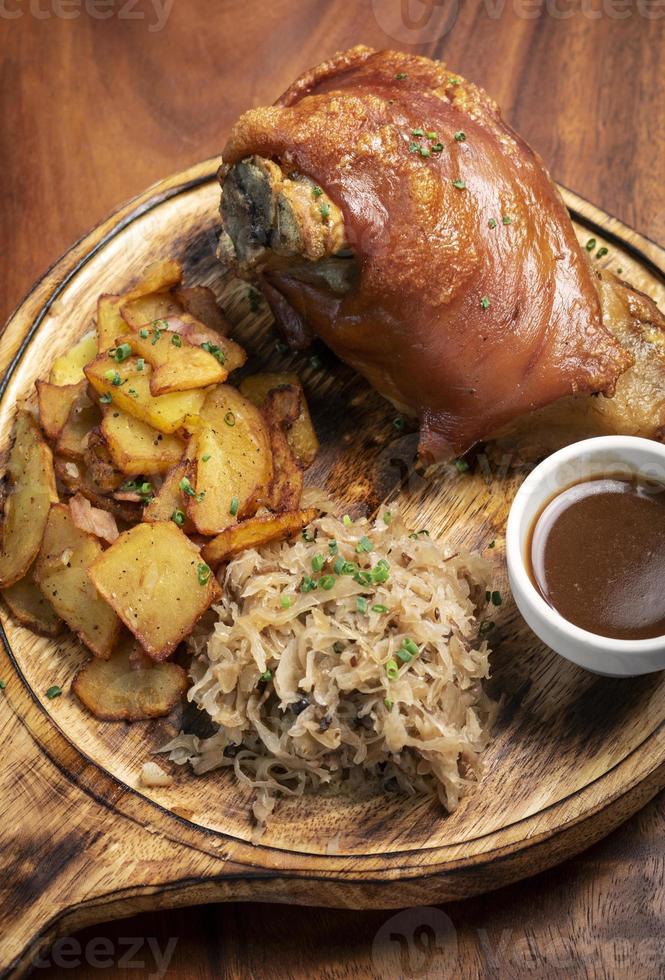 jarret de porc traditionnel allemand schweinshaxe avec choucroute et repas de pommes de terre photo