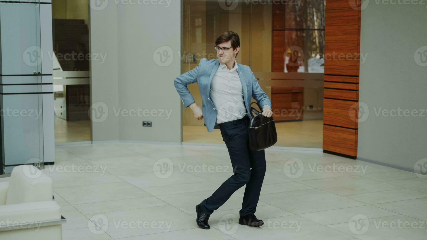 fou homme d'affaire dansant avec mallette dans moderne hall à l'intérieur seul photo