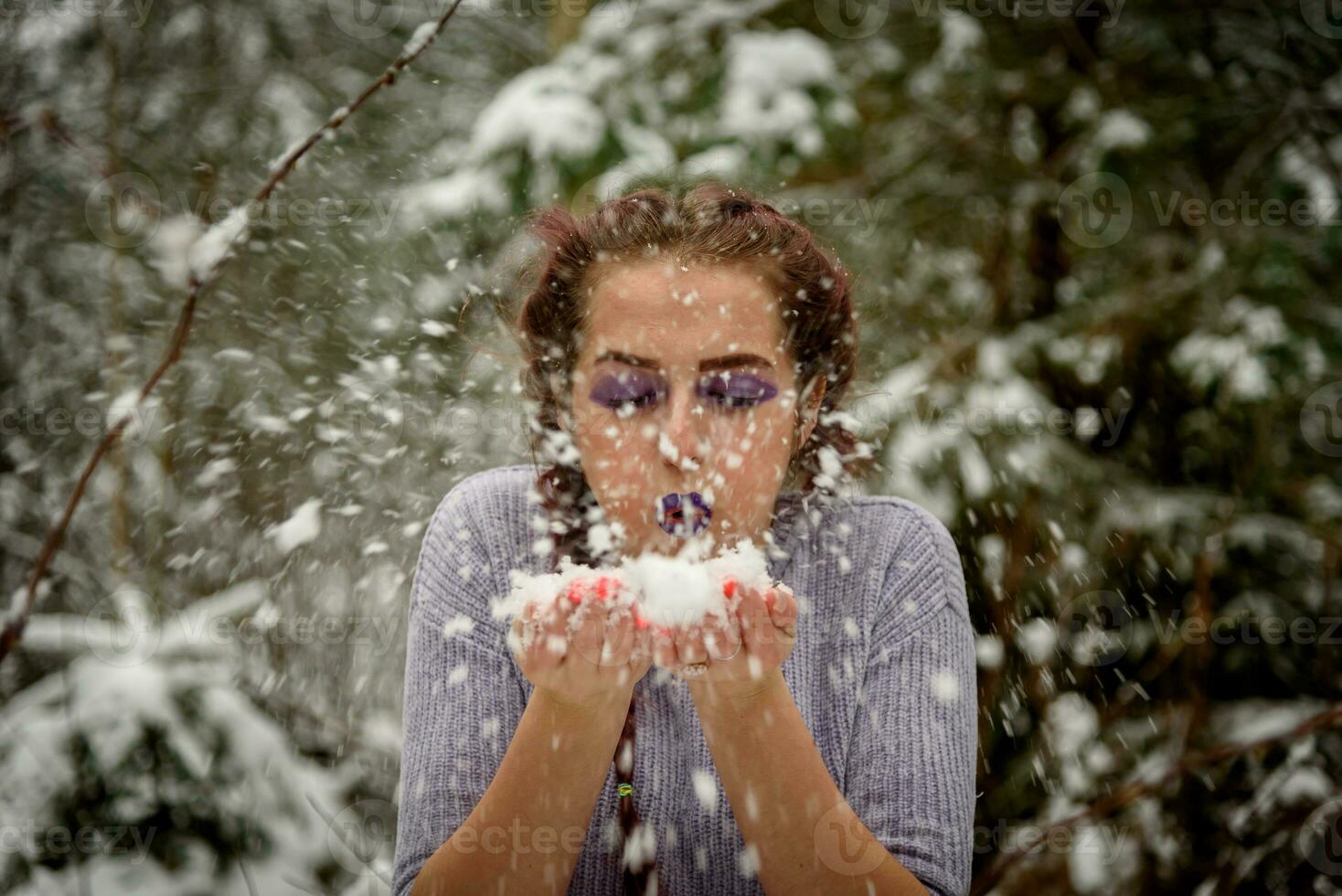 magnifique fille soufflant neige de sa mains. Extérieur hiver portrait. photo