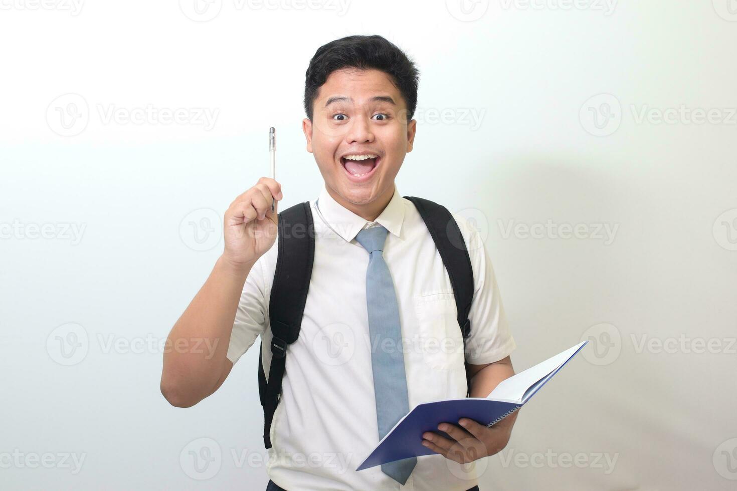 indonésien Sénior haute école étudiant portant blanc chemise uniforme avec gris attacher l'écriture sur Remarque livre en utilisant stylo. isolé image sur blanc Contexte photo