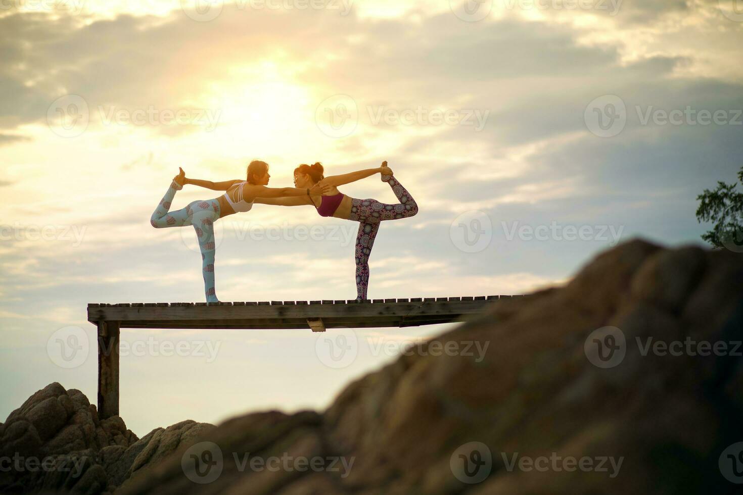 des couples de femme en jouant yoga pose sur plage jetée avec matin Soleil lumière photo