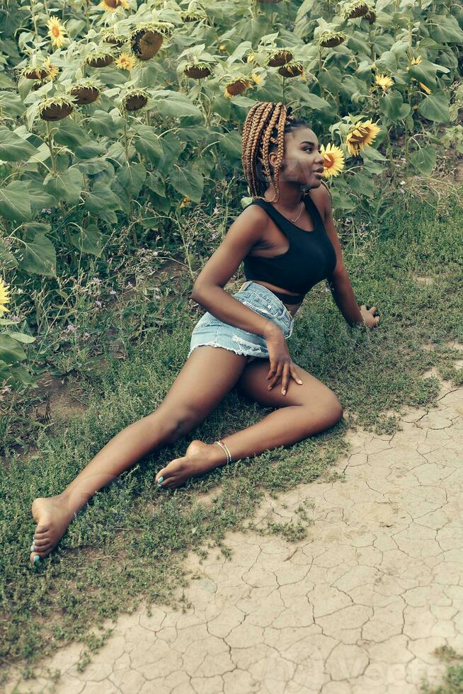 africain américain fille dans une champ de Jaune fleurs à le coucher du soleil photo
