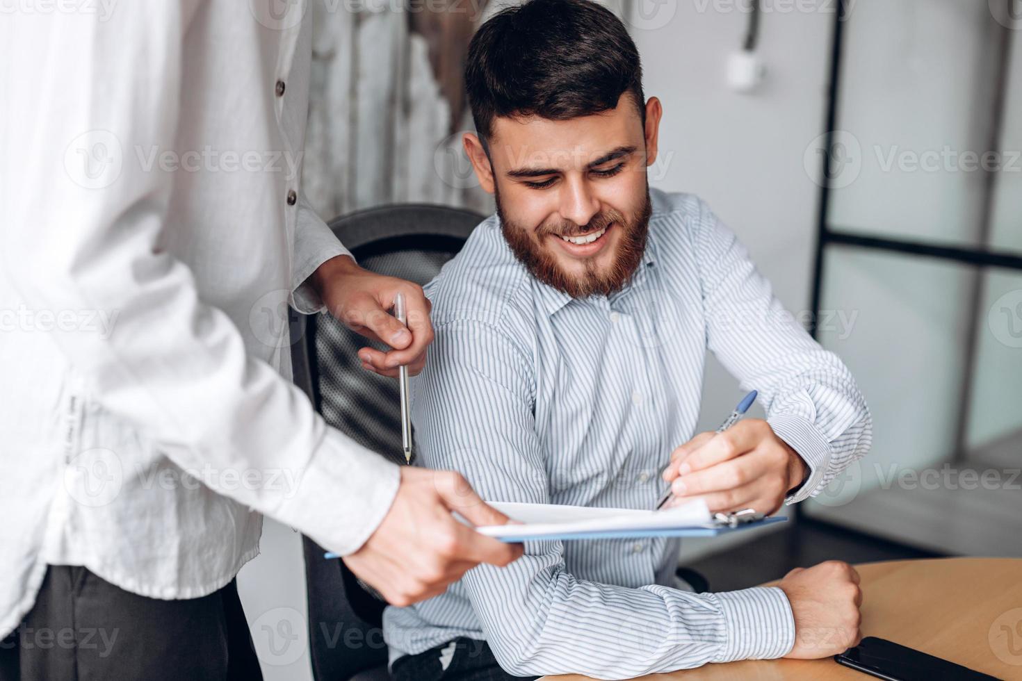 bel homme souriant signe des documents importants photo