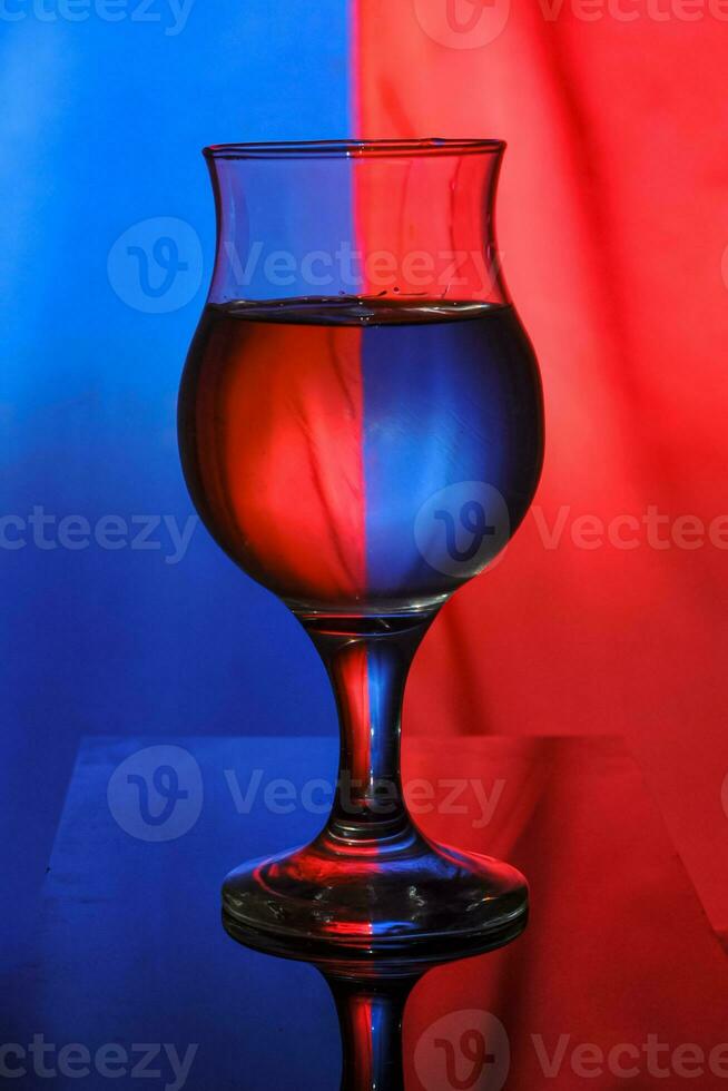 une du vin verre rempli avec l'eau sur une bicolore Contexte crée lumière diffraction et réflexion photo